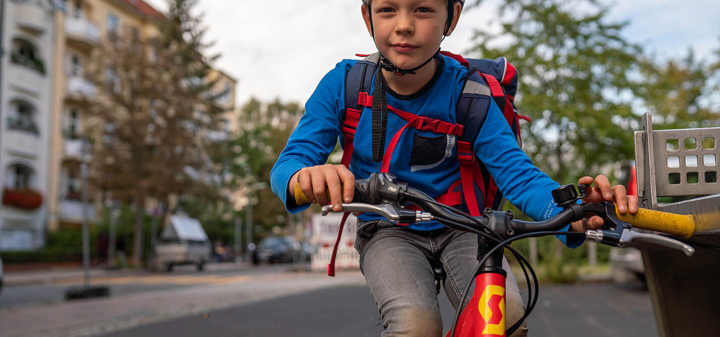 Ein Junge mit Schulranzen fährt mit dem Rad.