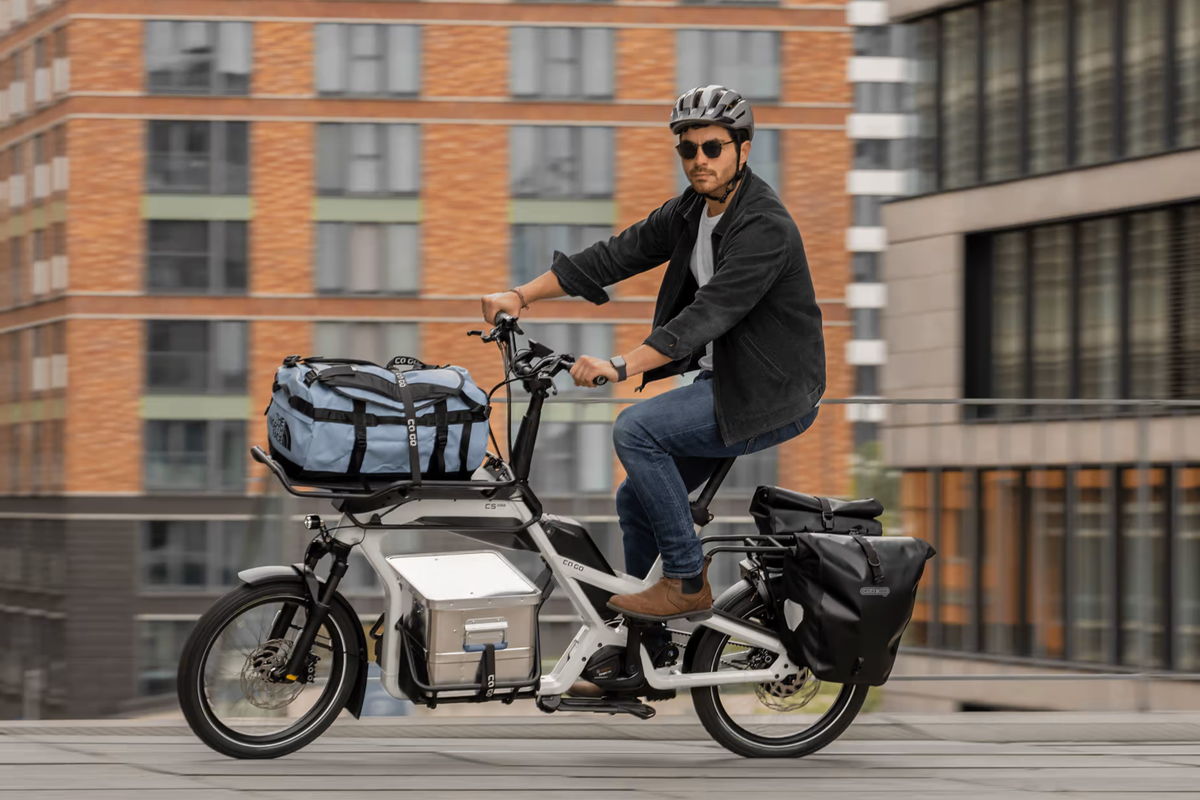 Eine beladenes CaGo Lastenrad auf der Straße, gefahren von einem Mann. 