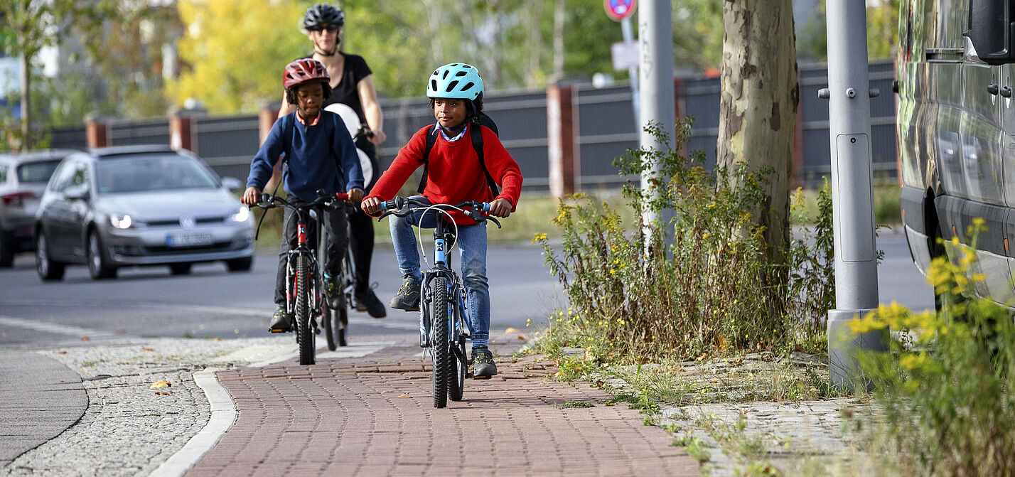 Kinder mit Helmen auf einem Radweg