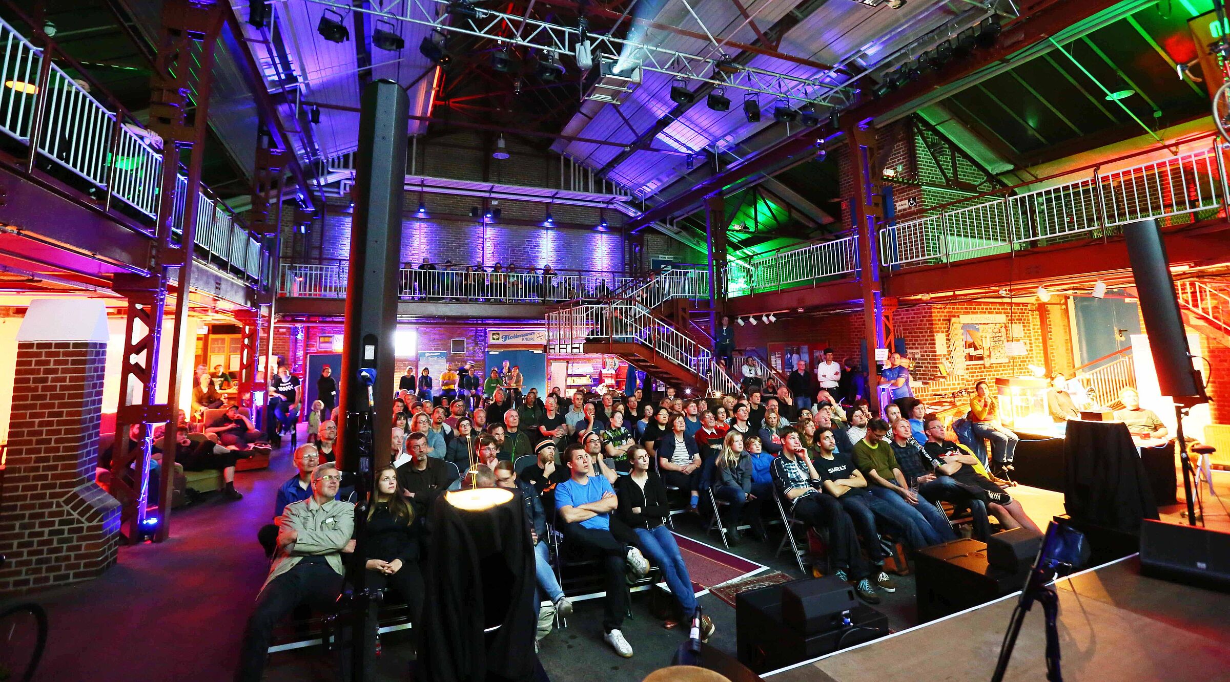 Das Bild zeigt das Publikum des Cycling Film Festival, die sitzend auf Stühlen einen Film schauen.